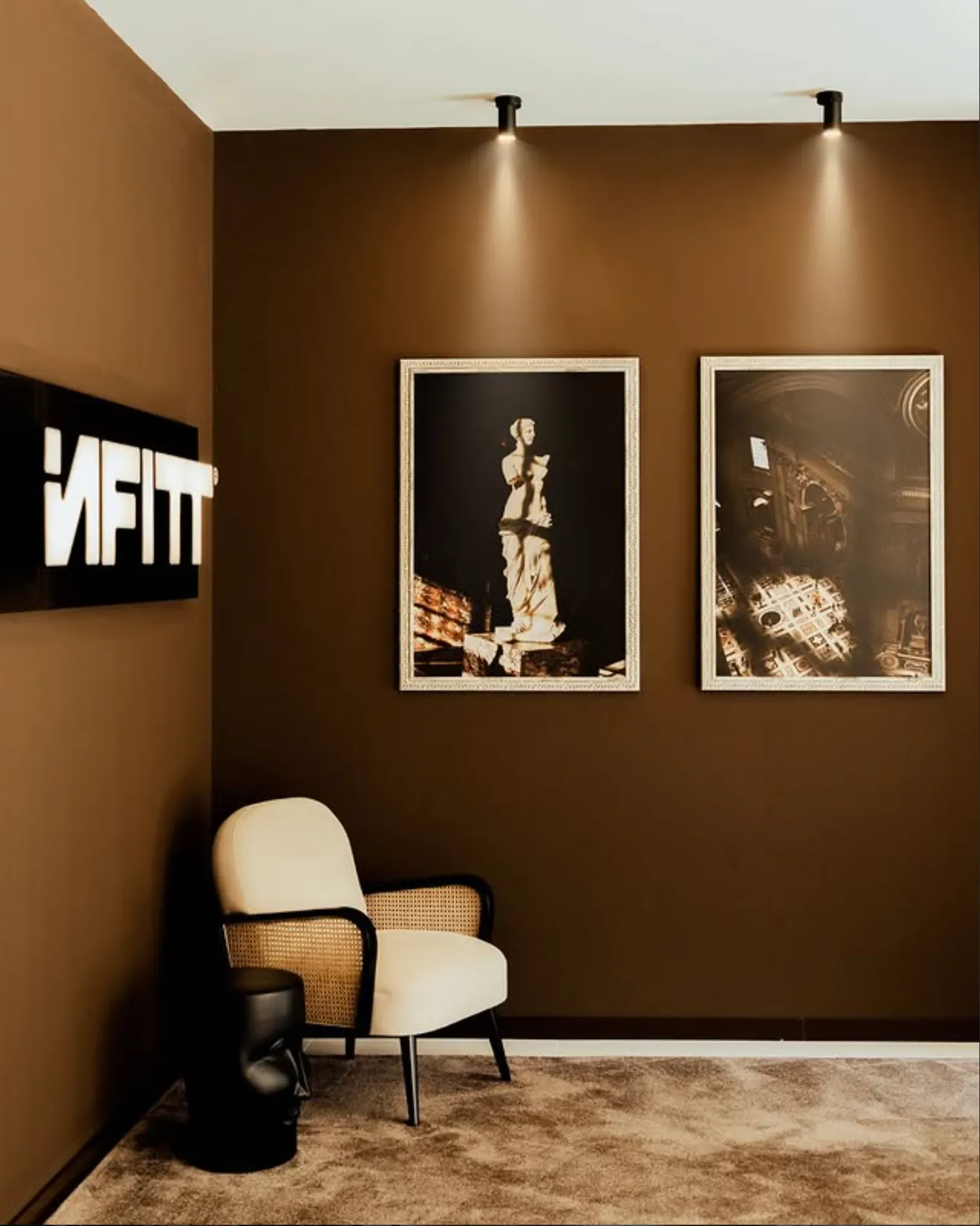 Receção do estúdio Infitt com logótipo iluminado e cadeirão em tons creme